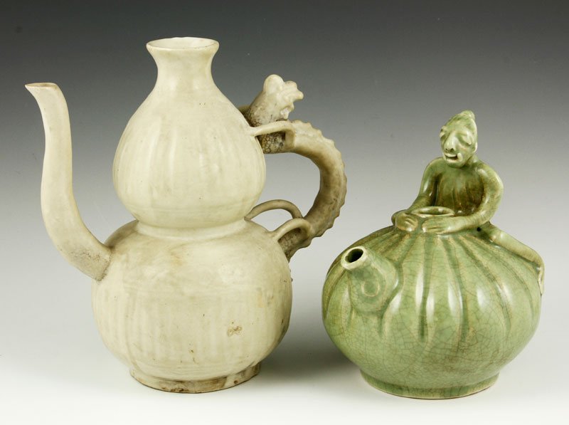 Southeast Asian Kendi Vessels: Pair of Kendi vessels, Southeast Asia, one green celadon glaze, decorated with the figure of a man sitting on the handle, 6 1/2" h; the other white celadon glaze, decorated with a dragon handle, 8" h.