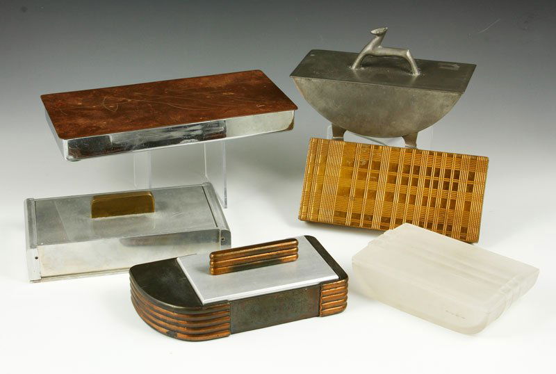Six Art Deco Cigarette Boxes: Group of six Art Deco/Machine Age cigarette boxes, circa 1930, to include Rice Pewter, shape 588 with deer finial 6 5/8” l, Revere, stainless and copper, 9 1/8” l and four others.