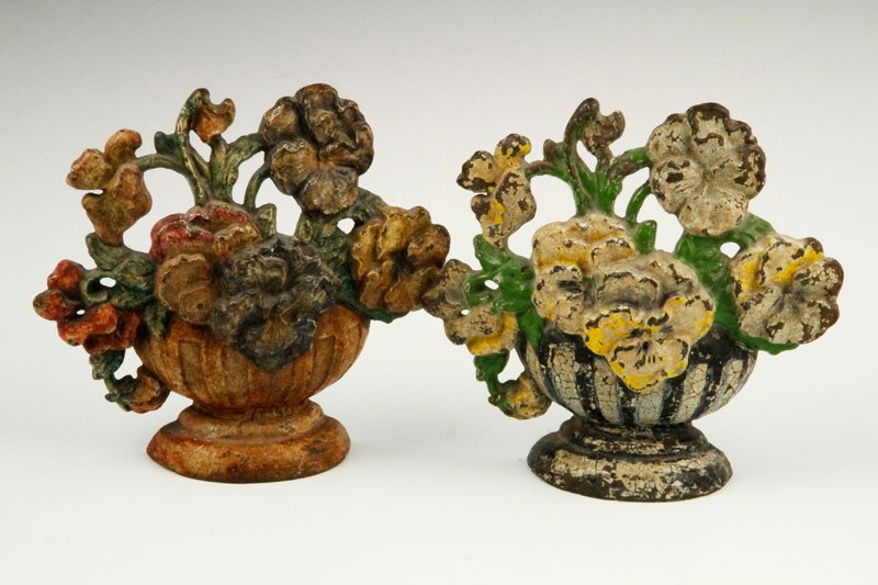 Lot of 2 Cast-Iron Door Stops: Pair of early cast-iron door-stops, one with bouquet of white pansies and green leaves in black and white striped urn, second with pansies in dark yellow and red in dark brown urn, 6 3/4".