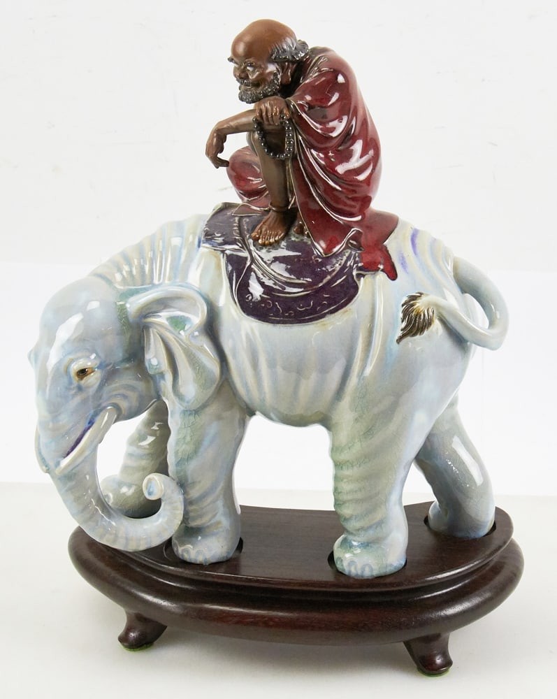 Japanese Porcelain Figure, Scholar Riding Elephant: Japanese porcelain figure of scholar riding elephant, on wood stand. 14" x 11" x 5". Provenance: Estate of David and Sarah Martin, Montecito, California.