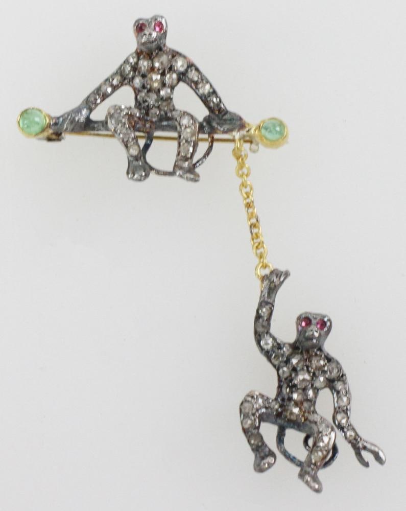 9k Gold, Sterling, Diamond and Emerald Monkey Brooch: 9k yellow gold and sterling monkey brooch/pendant, approximately 0.50 ctw of rose cut diamonds, approximately 0.30 ctw of emeralds, and approximately 0.06 ctw of rubies. 2" H x 1 1/4" W.