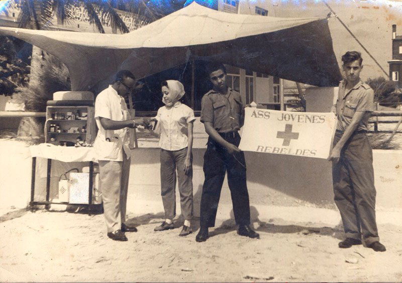 Photograph of Estevez and The Association of Young Rebe: Photograph of Argentina Estevez and the Association of Young Rebels, inscribed verso "Brigada de Primaros Auxilios' de la Asociacion de jovenes rebeldes", "Base 'Frank Pais' Playa Guanabo - Habana, Ju