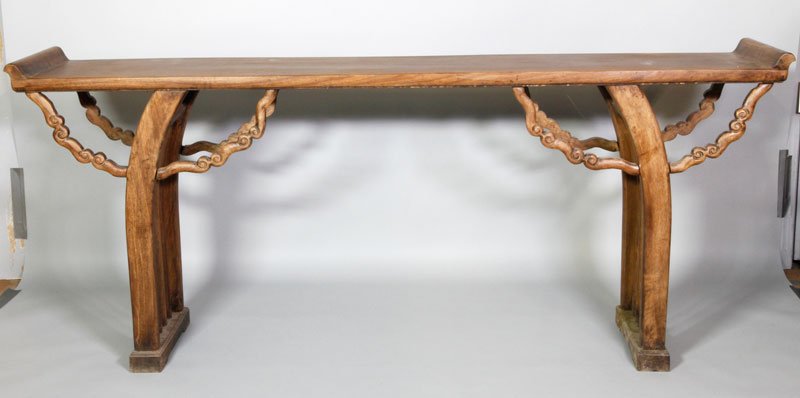 Chinese Qing Huanghuali Altar Table: Huanghuali wood altar table, China, Qing Dynasty, the flat top ending in gently curled edges, the curved legs supported by linked clouds on either side, 83" x 35 1/2" x 15".