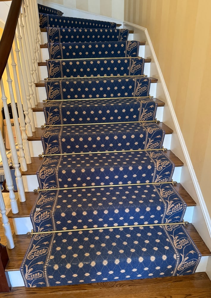 Custom-made Blue Staircase Rug with Floral Border: Custom-made blue staircase rug having a gold floral design on border. Includes brass stair rods. 2' 9" W, 4' 9" W at turn; 34' L. PLEASE NOTE: Item to be picked up at 129 Commonwealth Ave, Boston. Dea