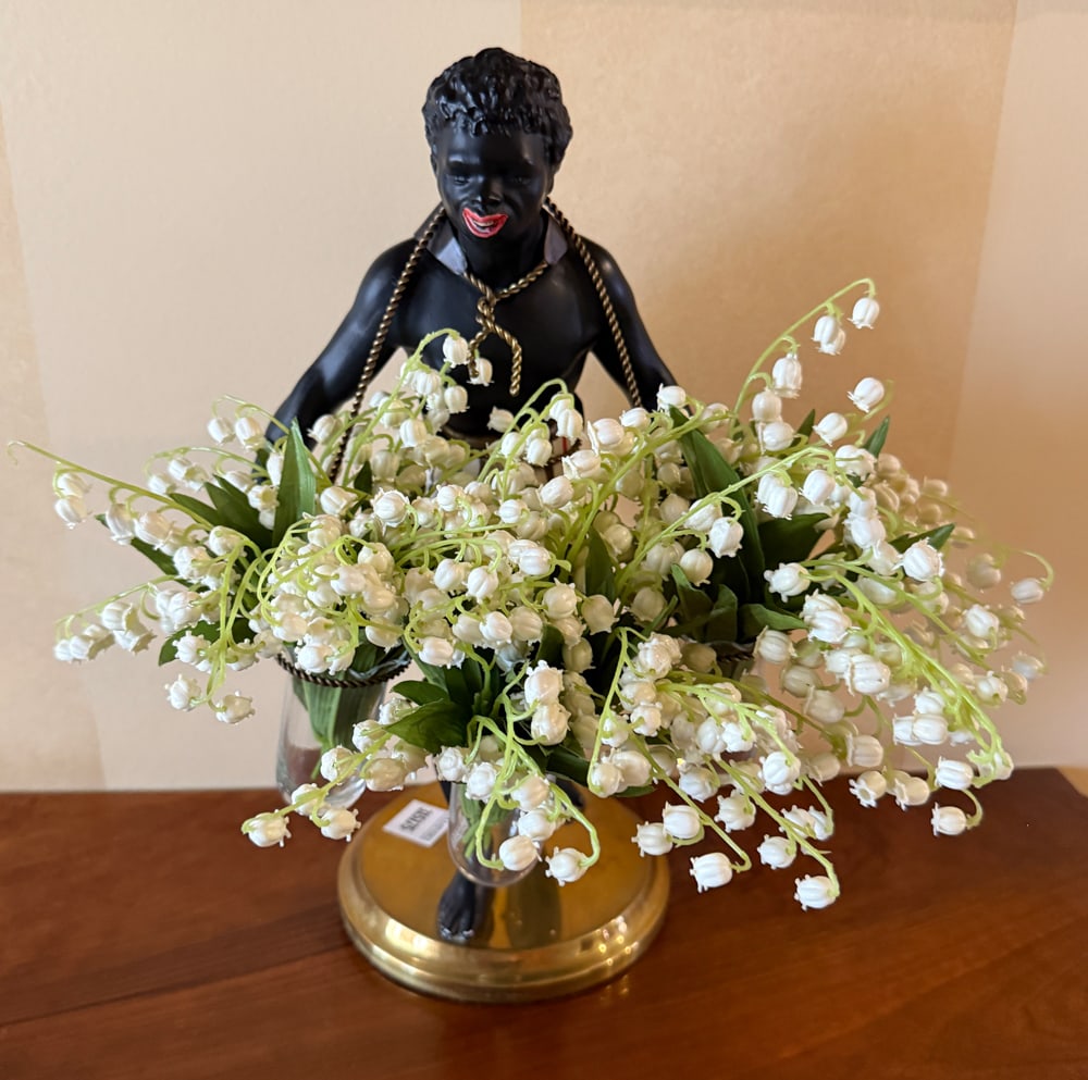 Vintage-style Bouquet in Vase Held by Black Figure: Vintage-style decorative bouquet of lily-of-the-valley flowers featuring a black figure holding vase, 13" H x 8" W x 10" D. PLEASE NOTE: Item to be picked up at 129 Commonwealth Ave, Boston. Deadline 