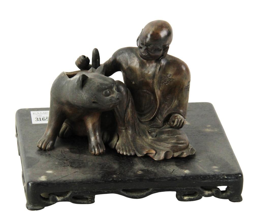 Japanese Terra Cotta Man with Cat: Japanese terra cotta man with cat, on wood base, 6 1/2 x 7 x 5 1/2 on stand. Missing lid. Provenance: Estate of the late Joseph W. Haley, of Pride's Crossing, Massachusetts.