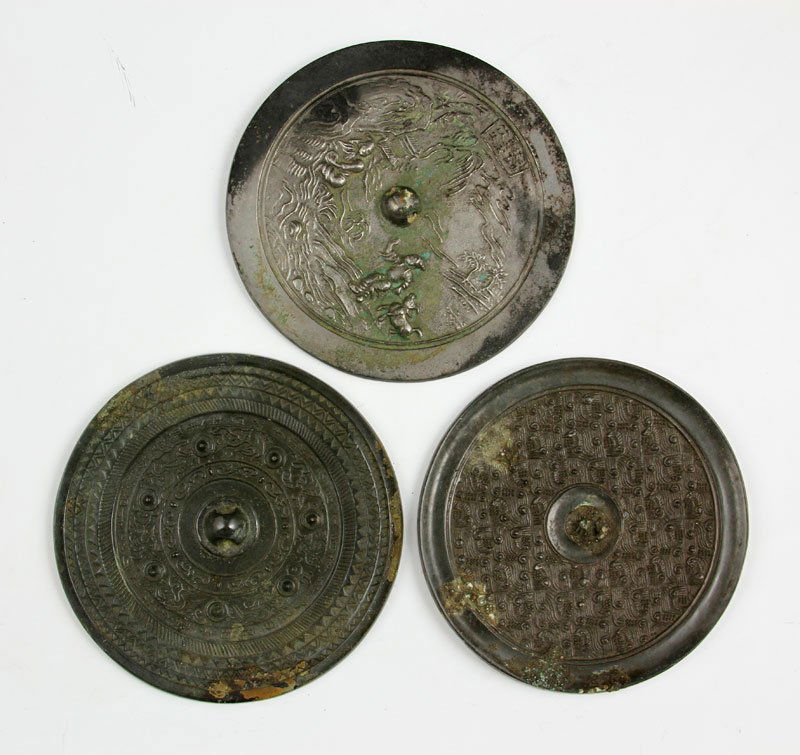 Chinese Bronze Mirrors: Three bronze mirrors, China, one carved with figures in a landscape, the others incised with archaic patterns, largest 5" dia.