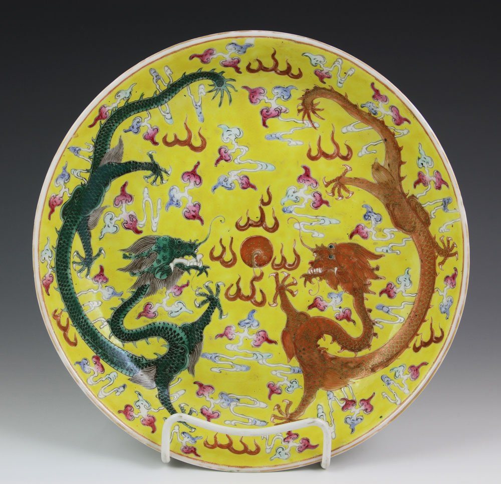 Chinese 20th C. Famille Jaune Plate: Famille jaune plate, Chinese, early 20th century, decorated with dueling dragons chasing the flaming pearl amid clouds over a yellow ground, six-character Guang Xu mark and three floral vignettes on b