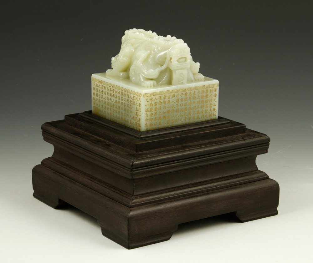Chinese Carved White Jade Seal: Carved white jade seal, China, the tall square platform covered on all sides with gilt calligraphy and a Greek key scroll border around top edge, surmounted by double headed mythical beast intricately