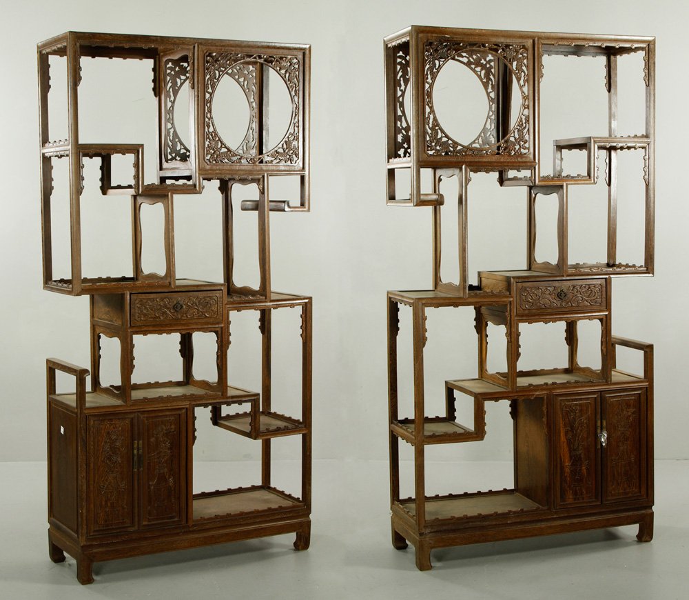Pr. Chinese Carved Bookcases: Pair of carved bookcases, China, with geometric openwork shelving, having two-drawer cabinet at base, one drawer at center, and square compartment at top carved and pierced with floral motifs in shape