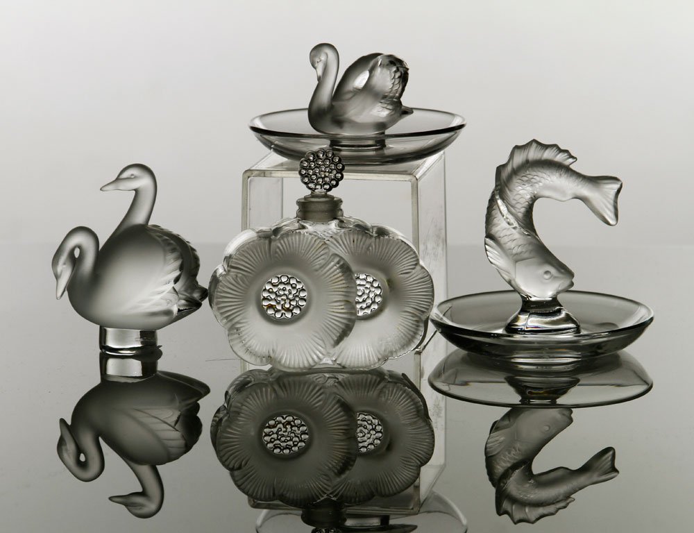 3 Lalique Vanity Items: Set of three Lalique vanity articles, to include: perfume bottle, "Deux Fleurs", #11301; pin tray, "Goujon", #10717; pin tray, "Cygne", #10707; cachet, "Deux Cygnes", #10608; cast colorless glass, mar