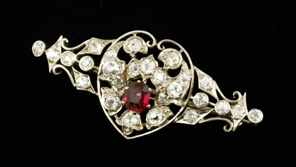 Edwardian 14K Diamond and Ruby Brooch: Edwardian 14K white gold, diamond, and ruby brooch, mixed cut natural ruby approximately .57 CTW, twenty six diamonds approximately 1.15 CTW, approximately 6.81 g. TW, 1 5/8" w. Includes appraisal cer