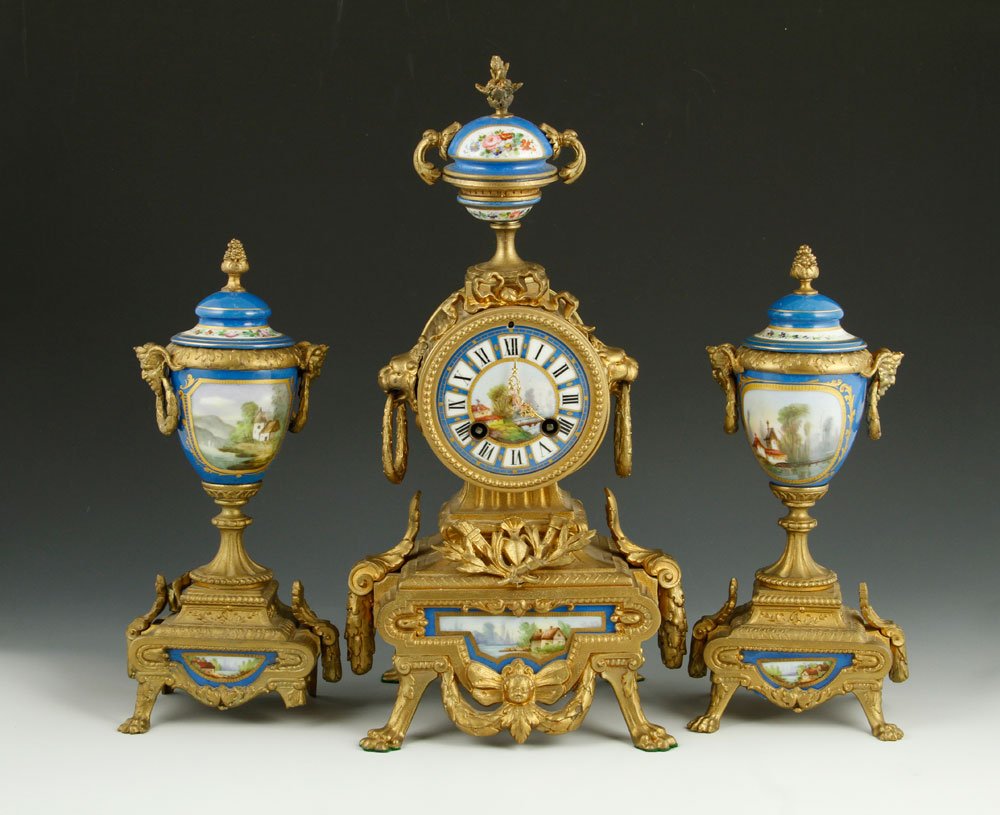 19th C. French Sevres Garniture Clock set: 19th century French Sevres garniture clock set, porcelain, with gilt white metal decoration, 14" h x 7" w (clock), 10" h (urns). Provenance: From the Estate of Mary L. Alchian, Palm Springs, CA.