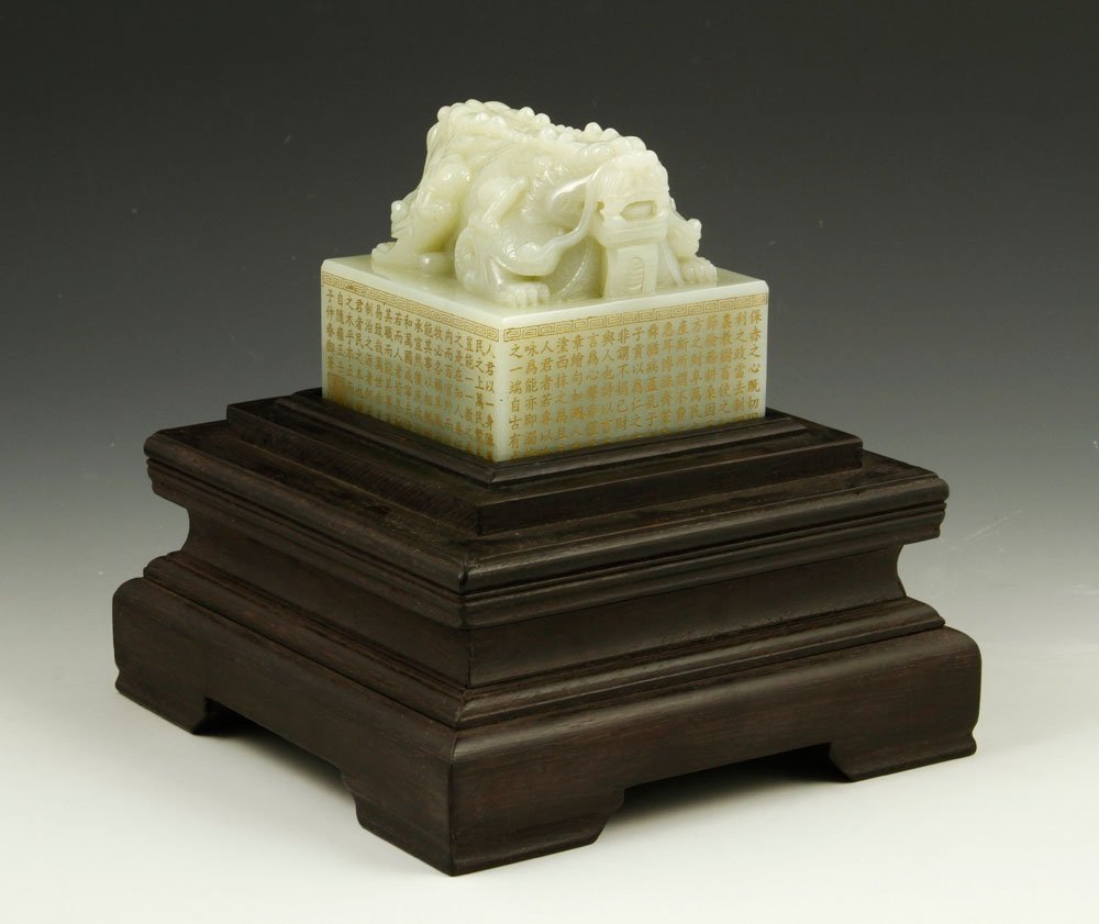 Chinese Carved White Jade Seal: Carved white jade seal, China, the tall square platform covered on all sides with gilt calligraphy and a Greek key scroll border around top edge, surmounted by double headed mythical beast intricately
