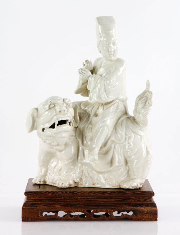 Chinese Blanc de Chine Figure: Figure of a officer sitting on foo dog, with carved wood base, China, Ming dynasty style.