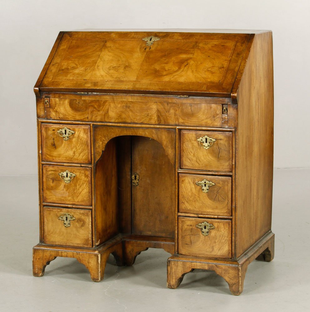 1710 English Walnut Kneehole Desk: English Queen Anne kneehole desk, figured walnut and inlaid, figured and feathered band top and fall front, fitted interior with secret compartments, six oysterwood drawers, original brass escutcheon 