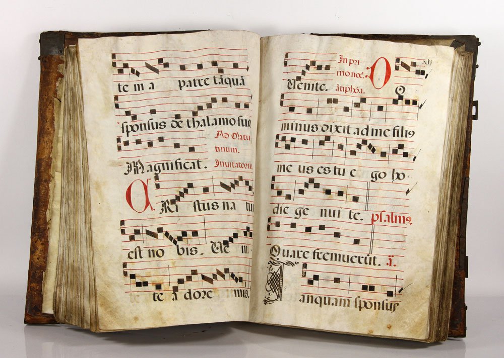 Continental Baroque Antiphonal "Dominica Prima": Continental Baroque antiphonal "Dominica Prima," leather bound folio, with pierced brass scroll and spear corner enclosing illuminated vellum leaves, approximately 150 pages, 25" h x 17" w. Provenance