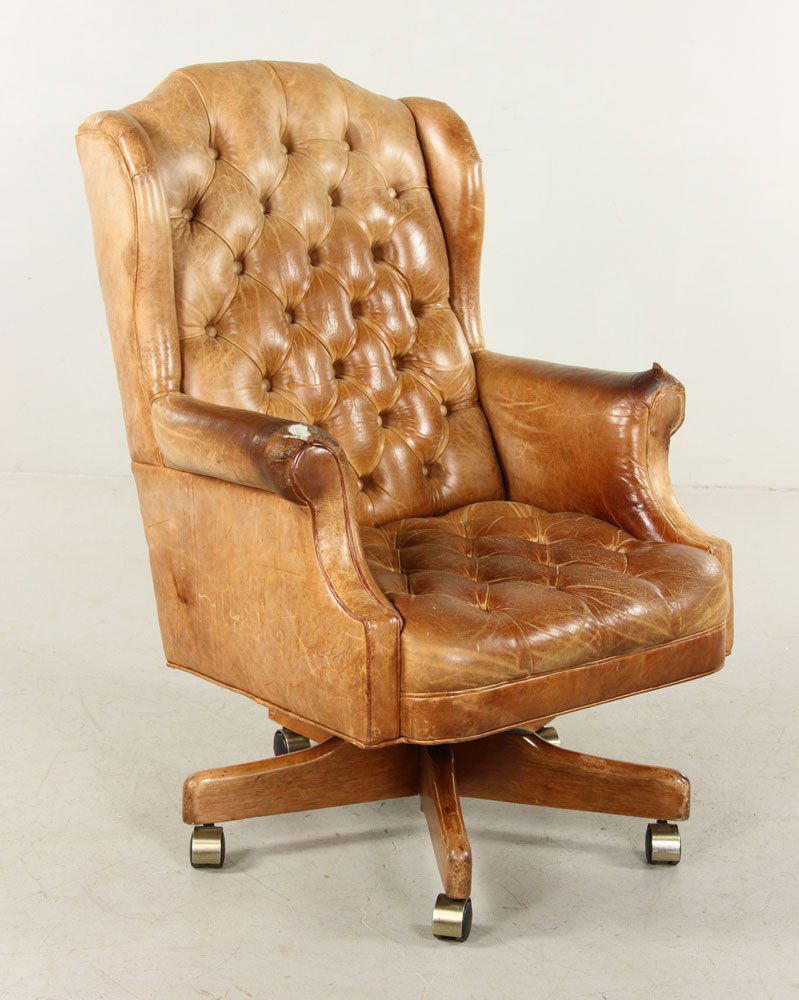 Executive Desk Chair: Fully upholstered russet leather wing back executive desk chair, upholstered in a supple button tufted leather, the wings down curving to rollover arms. Provenance: From the unreserved estate of a pro