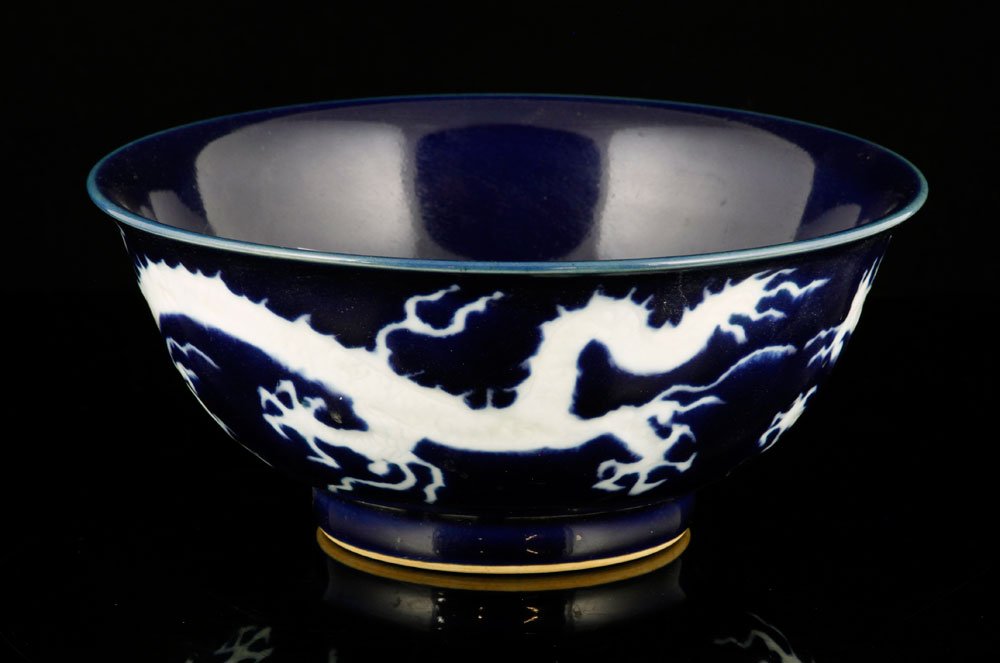 Chinese Blue Glazed Bowl: Chinese bowl, blue glazed porcelain, with white carved dragon pattern, Xing mark on base, 3 1/2" h x 8" dia. Provenance: from a Massachusetts estate.