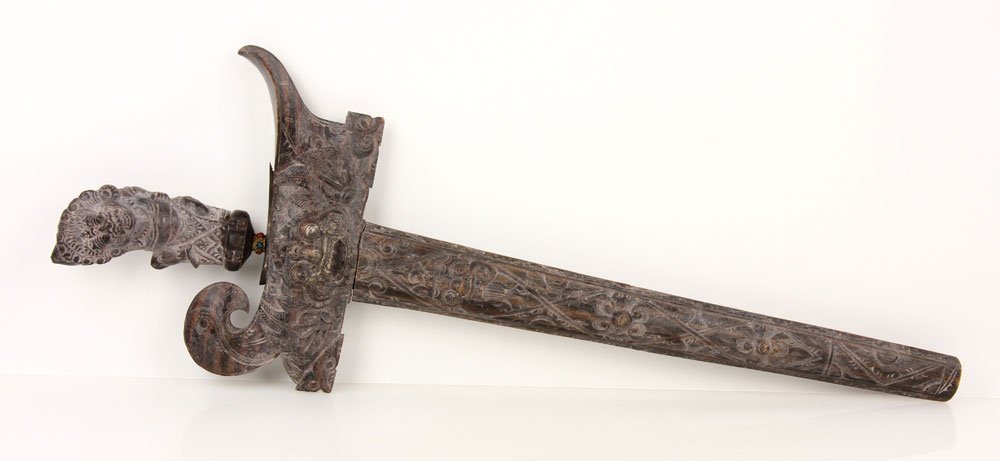 Wavy Kris: Kris, wavy meteorite blade, intricately carved wooden hilt and scabbard; 14 1/2" l (blade), 21" l (overall). Provenance: From the unreserved Vincent J. Vabri Edged Weapon Collection.