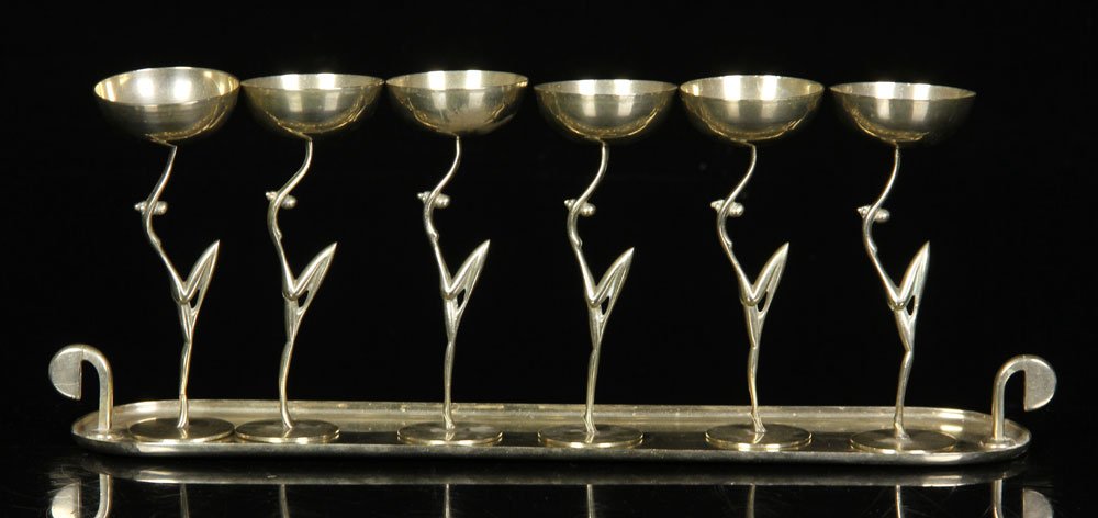 Karl Hagenauer Liqueur Set: Karl Hagenauer (Austrian, 1906-1986), liqueur set, with six glasses and tray, nickel-plated brass, stems fashioned to resemble nude female dancers, signed "WHW" on base, 14 1/8" l x 3 1/4" w (tray), 5