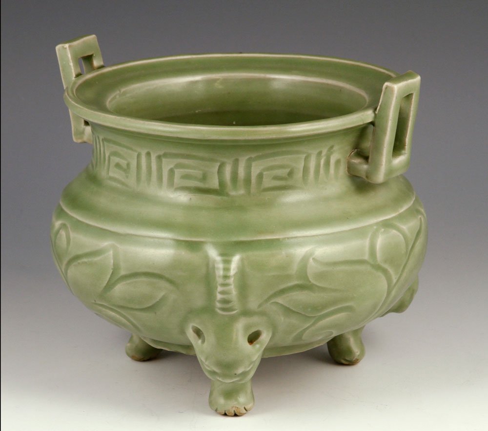 Chinese Celadon Censer: Celadon porcelain censer, China, Ming Dynasty or later, carved with large flower pattern, with rectangular handles and three foo lion shaped legs, 6" h x 7 1/2" w.