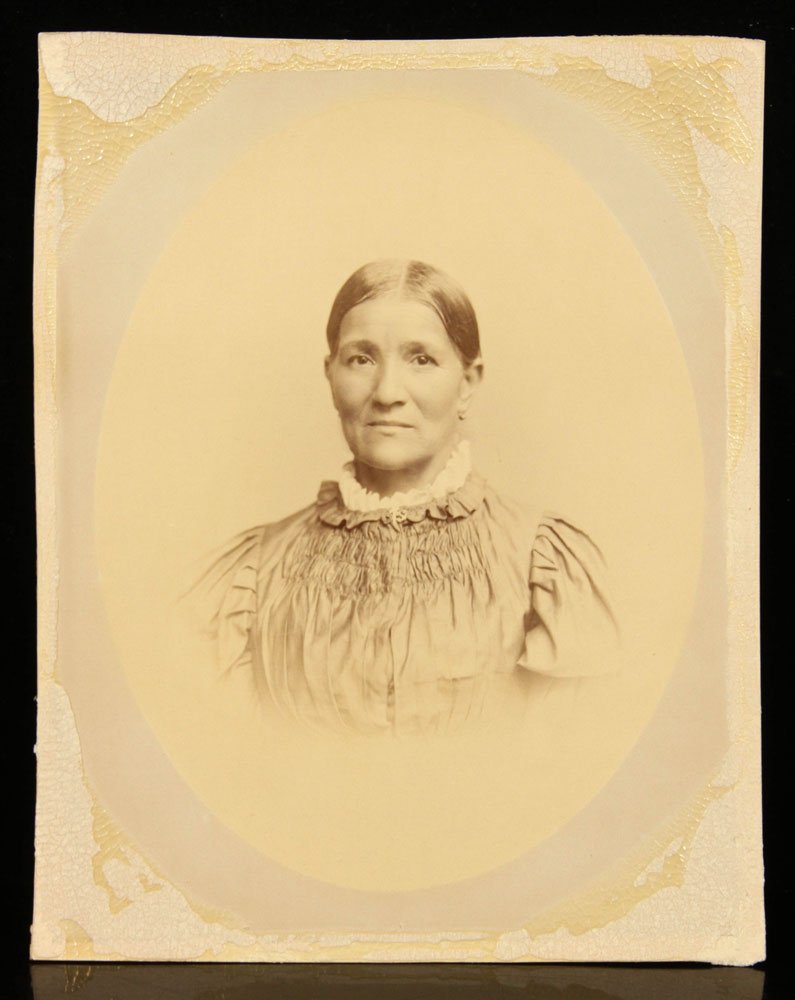 Antique Native American Woman Albumen Photograph: Antique albumen photograph, showing a Native American woman in settler's dress, 12 1/2" h x 10" w. Provenance: From a Massachusetts estate.