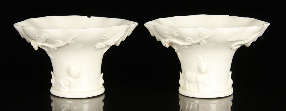 Pr. Chinese Blanc de Chine Cups: Pair of Blanc de Chine porcelain cups, Chinese, with leaf-shaped rim and high foot, relief decoration showing deer, dragon, crane, plum branch and lion, 3 1/2" h x 6" dia. Provenance: From a Massachus