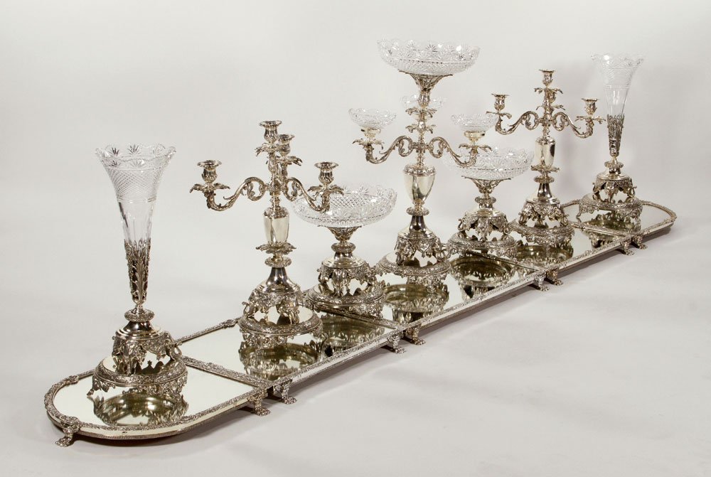 Victorian Style Silver Plated and Glass Surtout de: Victorian style surtout de table, silver plate and cut glass, with Indian motif, twelve pieces total, with one extra glass, two pieces are 11 1/2" h x 10" w, other two are 14 1/2" h x 8" w. Provenance