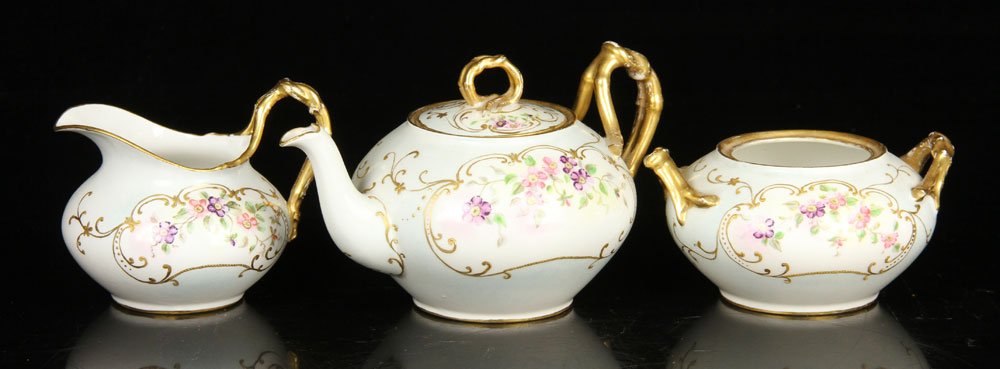 French Limoges Tea Set: Limoges porcelain tea set, French, decorated with flowers and gilt accents, bases marked "JP / L / France" in green, to include: teapot (8 1/2" w, including spout and handle), creamer and sugar (missi