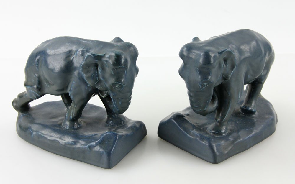 Pair Of Rookwood Pottery Elephant Bookends: Pair of Rookwood Pottery elephant bookends with blue matte finish, maker's mark on base along with 2444C for shape number, and XXI to designate the year 1921, approximately 6" h x 6 1/2" l. Provenance