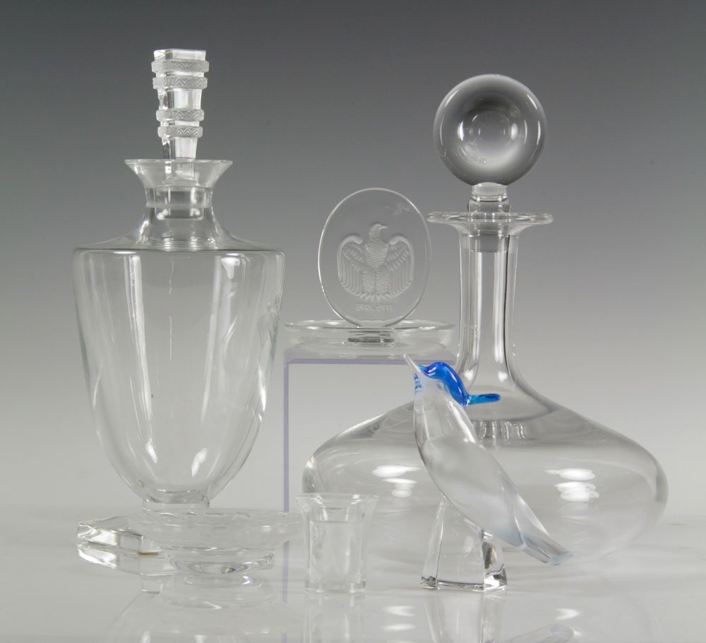 6 Pieces of Lalique Crystal: Lot of six pieces of Lalique crystal, to include: two decanters, shot glass, dish carved with birds around rim, bird figure, and bicentennial eagle ring holder, tallest 11" h. Provenance: From a Flori