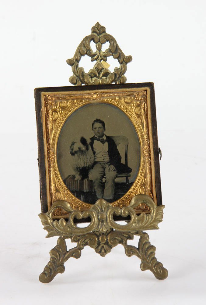Antique Tintype Of A Boy And Dog: Antique tintype of a boy and dog, in gold and leather frame, on bronze stand, 3 1/2" high x 3" wide (photo only), 7" high (on stand). Provenance: from the personal collection of Larry and Joy Redman o