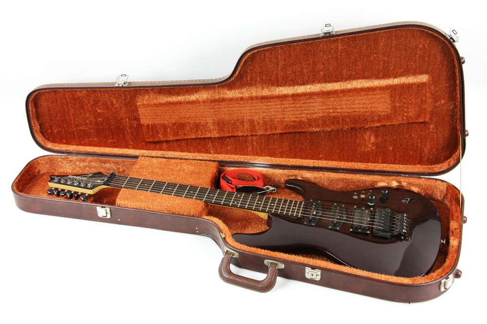 Ibanez Electric Guitar: Ibanez electric guitar, with red shoulder strap and case; small crack to body, missing battery plate.
