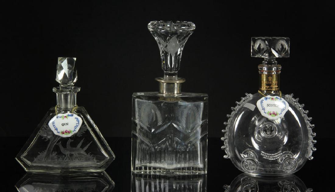 Three Glass Decanters: Lot of three glass decanters, to include: etched cut glass decanter decorated with pheasants, Baccarat Louis XV Remy Martin cognac bottle, and wheel cut crystal decanter with sterling top, tallest 11"