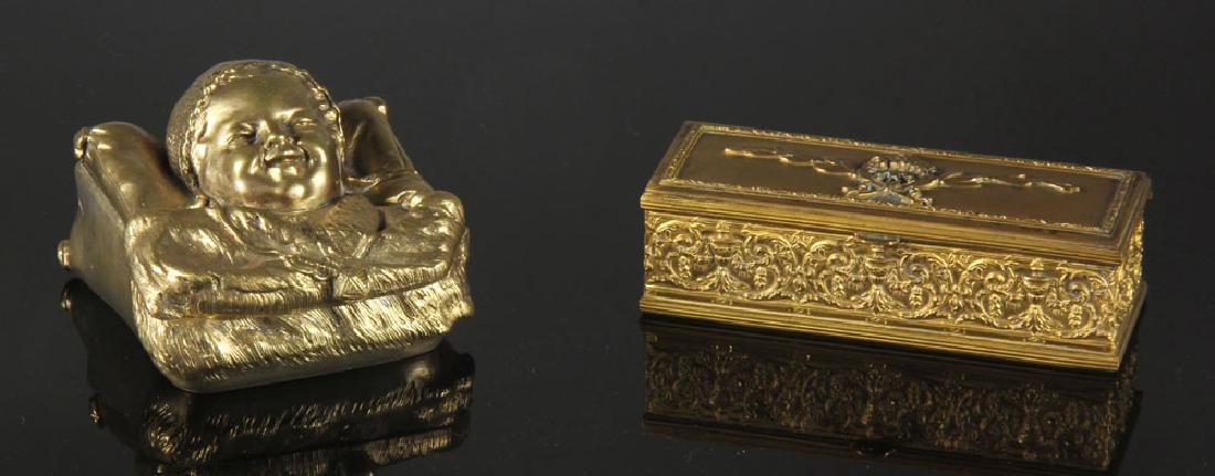 19th C. French Bronze Stamp Boxes: Two French bronze stamp boxes, 19th century, one with garland and wreath motif, one with figural lid in the form of a baby (3 1/2" sq). Provenance: From a Santa Barbara, California estate.