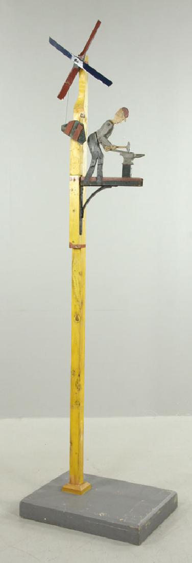 American Folk Art Whirligig: American folk art mechanical whirligig, late 19th to early 20th century, carved wood, showing blacksmith at forge with anvil, 90" h x 24" w x 18" w. Provenance: From the lifetime collection of Cheryl 