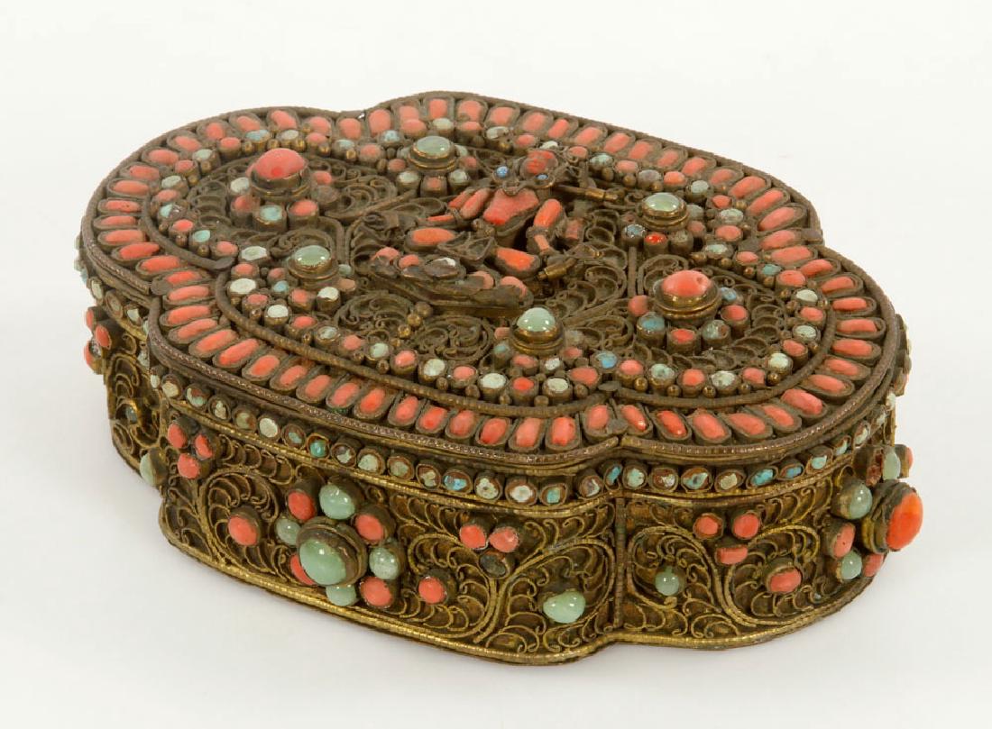 19th C. Nepalese Gilt Brass Box: Late 19th century Nepalese box, gilt brass with coral and turquoise, Buddha detail on lid, 2" h x 5 1/4" l. Provenance: From a New York estate.