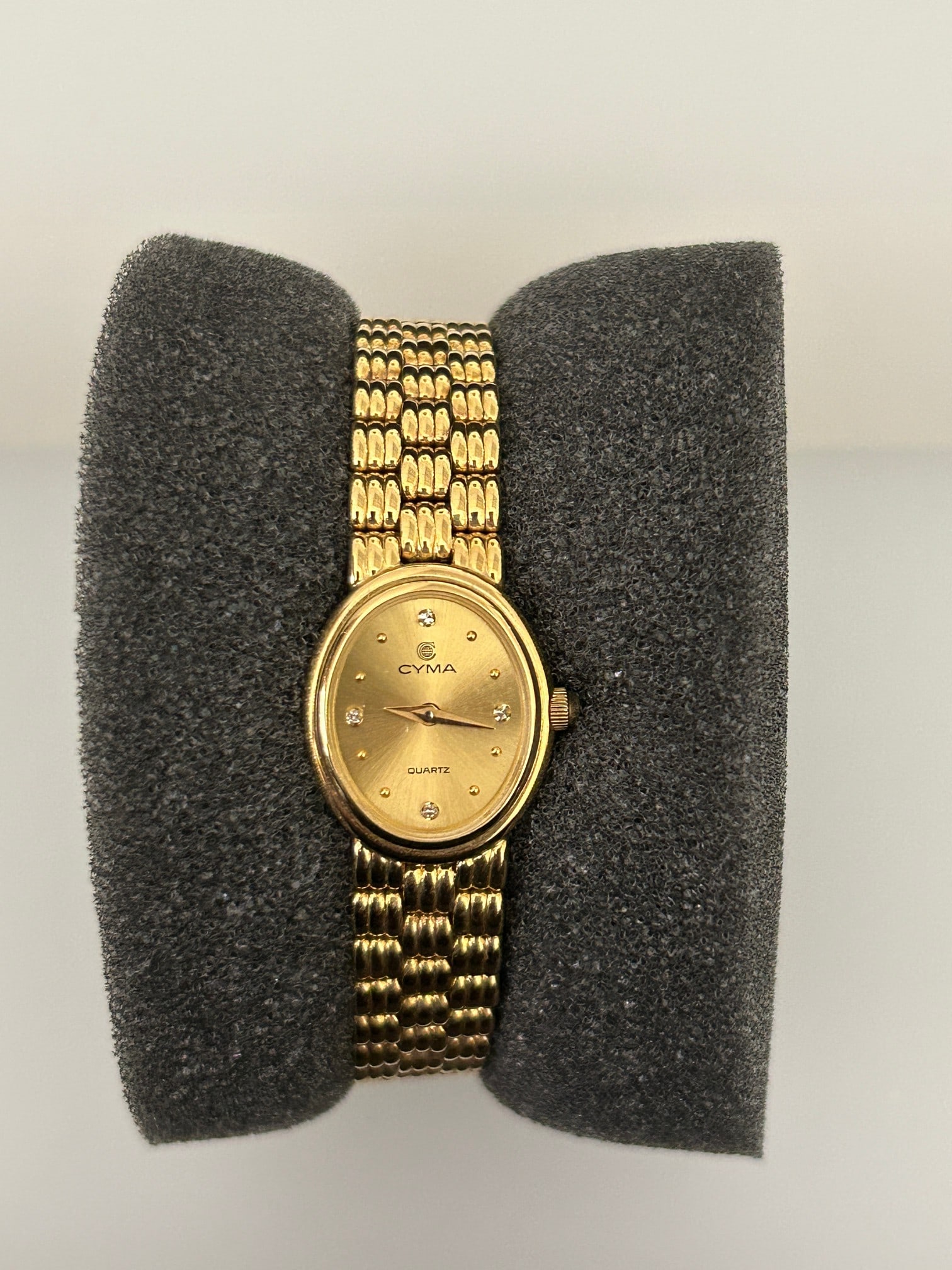 Cyma Ladies Yellow Gold Watch: This beautiful 18k yellow gold watch has four diamond markers, quartz movement and an 18k gold case and bracelet. The gold dial is inside a 15.5mm yellow gold case.
