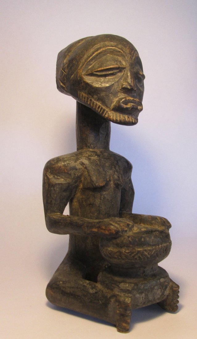 Hemba Drummer sculpture African tribal Art: Serene carved wooden sculpture of An ancestor Drummer from the Hemba of the Congo, Africa. With his tongue out and sitting with drum between his legs and feet, just as they would have held the Djembe 