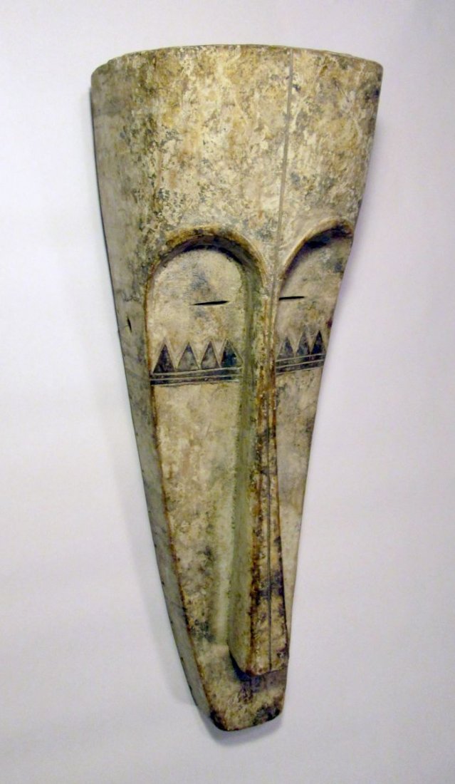 Long faced FANG N\'gil African mask: Carved wooden Mask from the Fang of Gabon, Central Africa. Long exaggerated mask face painted with white kaolin clay and accented with geometric linear designs. The Regalia Holes around the chin are a