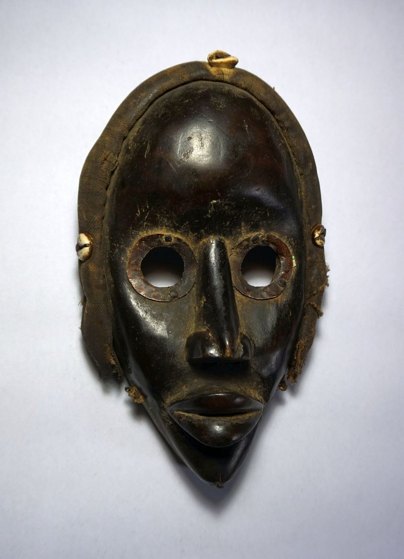 a Fine DAN African mask , African Tribal Art: Carved wooden mask from the DAN peoples of Cote d'ivoire , West Africa. Realistic wooden face mask with carved facial features metal accented eyes and pursed lips. Large domes forehead and with textil