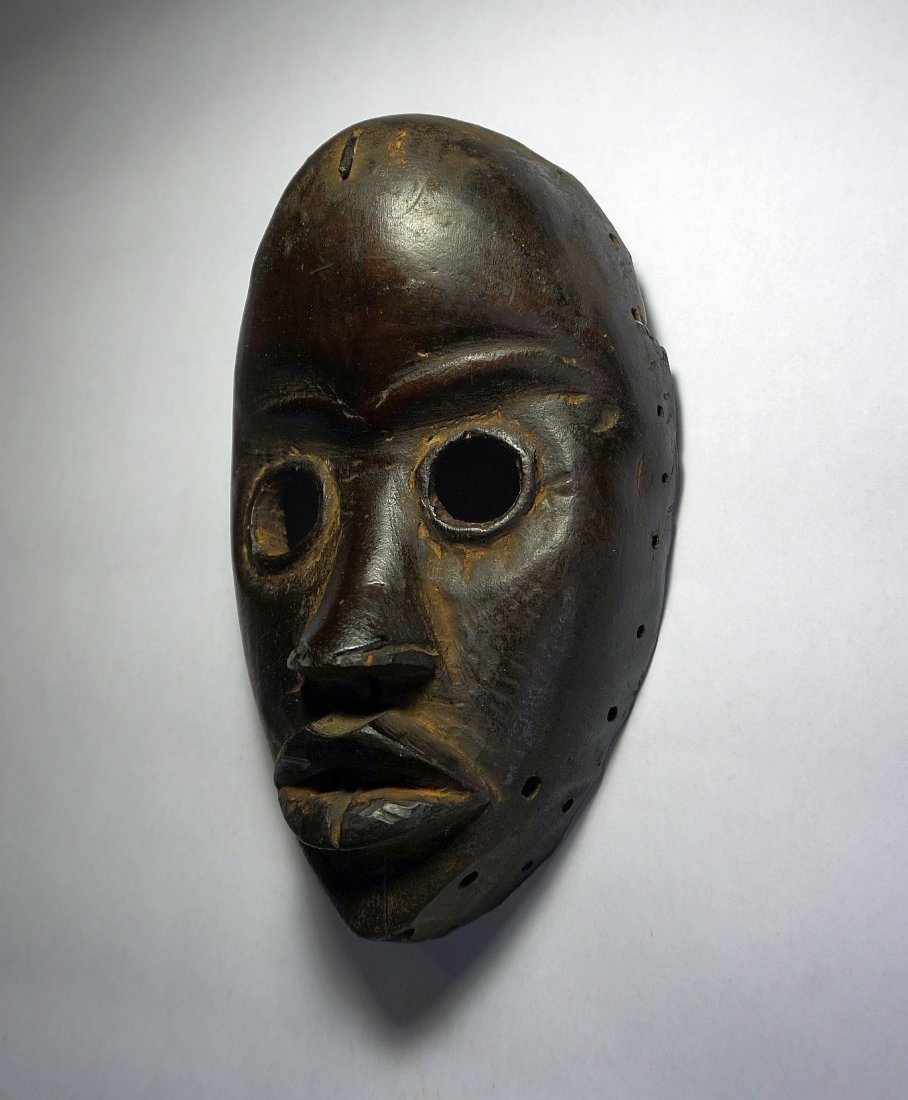 Old-Dan-African-mask-African Tribal Art: Carved wooden mask from the DAN peoples of Cote d'ivoire , West Africa. Realistic wooden face mask with carved facial features, large open eyes and pursed lips. Large domes forehead and with nail in f