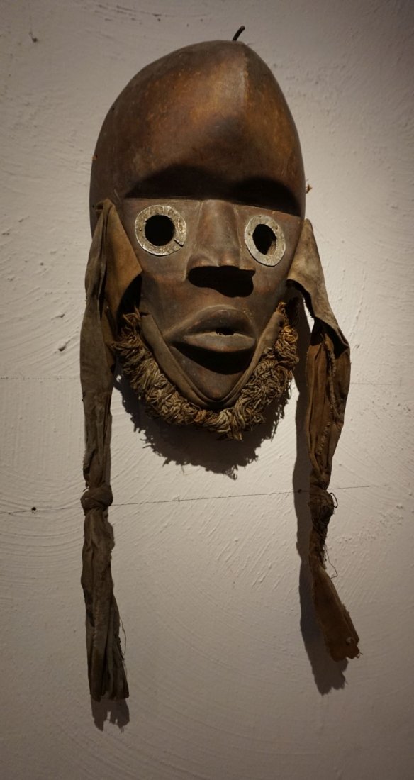 Dan Zakpai racer mask, African Art: Carved wooden mask from the Dan peoples of the Ivory Coast, West Africa. Accented with metal rings around the large open eyes and a raffia grass "beard". Such masks were used in annual village races d