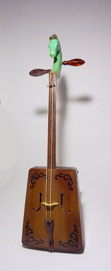 Horse head fiddle from Mongolia . The Morin khuur: Vintage carved wooden morin khuur or Horse head fiddle from Mongolia. The instrument consists of a trapezoid wooden-framed sound box to which two strings are attached. It is held nearly upright with t