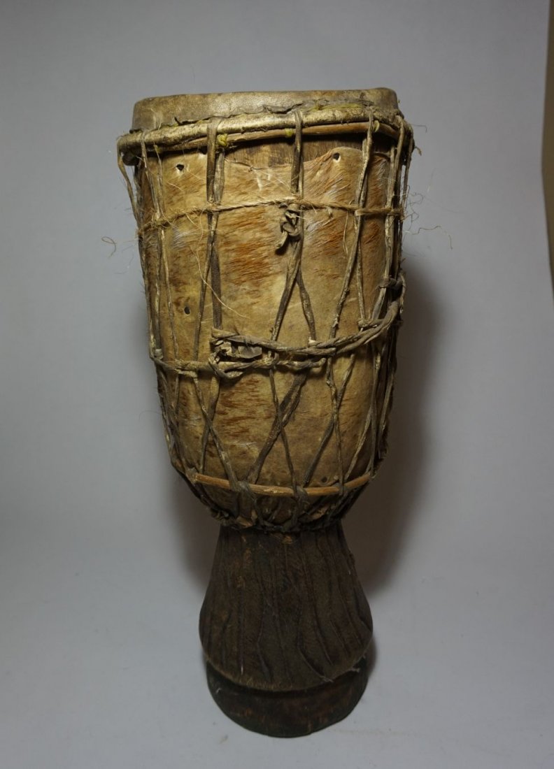 Old West African Djembe style drum, Tribal Musical: Old carved wooden drum in Djembe style from west Africa, Possibly Nigeria. Carved wood shell with animal hide decoration as well as goat skin head. Measures 18 x 7.5 inches.