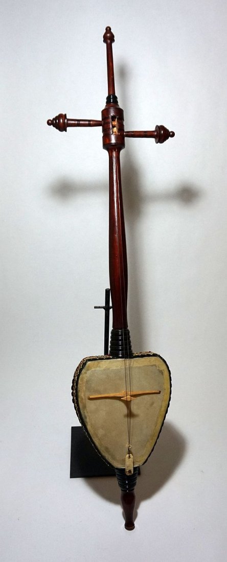 a Very Fine Indonesian Rebab Musical Instrument: Carved wooden body accented with textiles and covered with a very thin animal hide. The long neck and over sized tuning pegs. A Classic example. Measures 45 inches tall.