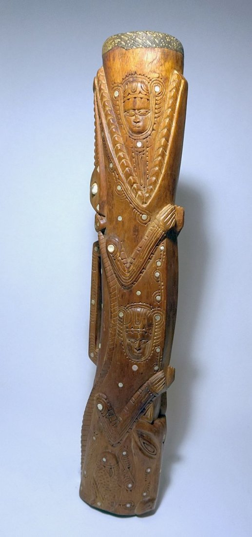 Massim Kundu Drum in Crocodile form with ornate design: Carved wooden drum with reptile skin head and ornate designs featuring a large crocodile and mask motifs, with inlaid abalone shell. Measures 29 inches tall.
