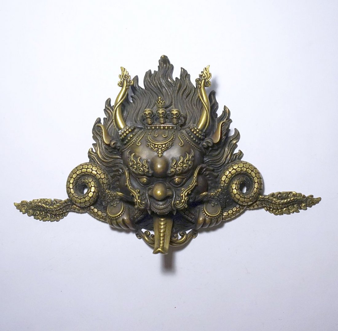 Very Fine Tibetan Wrathful Deity Bronze, Buddhist art: Very Fine Tibetan Wrathful Deity Bronze panel featuring a ferocious demon wearing a skull crown and devouring serpents. Age unknown but appears contemporary. Measures 15 x 10 inches.