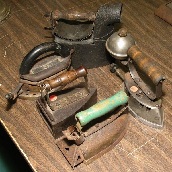 Lot of five various powered irons, cast iron, (1): Lot of five various powered irons, cast iron, (1) early slug or box iron with compartment for an inserted heated brick, 6" long (2) gas powered iron, 11" long, (3) charcoal iron with ruffle press hand
